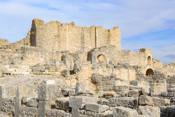 Ruins of the antique Roman city of Thugga in Tunisia, Africa.  Blue sky with clouds, old yellow stone walls