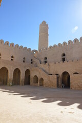 The inner yard and tower of VIII century arabic fortress (ribat) in Sousse, Tunisia, Africa. Blue sky, old arches, shadows and sunlight on the ancient stone walls