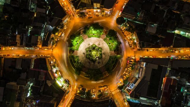 Top down aerial time lapse view of night traffic at roundabout in central Bangkok, Thailand, zoom out.