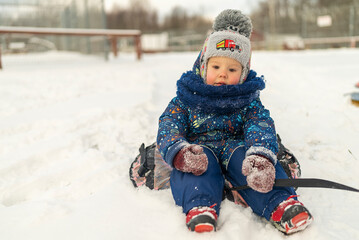 Fototapeta na wymiar little boy sit on tubing in a snow-covered slide winter fun.