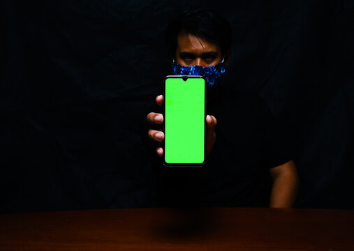 A picture with noise effect of green chroma key at smartphone with hand holding it insight. For technology, cybersecurity and information concept.