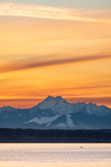 Sun sets over Puget Sound and the Olympic Mountains with colorful skies and a fishing pier