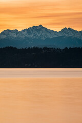Sun sets over Puget Sound and the Olympic Mountains with colorful skies and a fishing pier