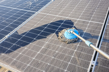 Man clean up the solar panels that are dirty with dust and birds' droppings to improve the efficiency of solar energy storage.