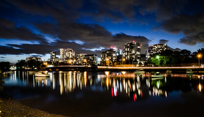Fototapeta premium Cityscape night shows its shadow on water and clouds on the sky at the port in Cook river, Sydney, Australia.