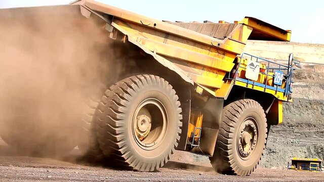 Mining dump truck close up. Large wheels of a mining dump truck. A large modern dump truck travels through the quarry
