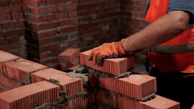 The builder is laying the bricks. The process of building a brick wall
