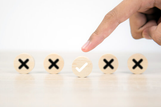 Hand choose check mark on wooden toy block stacked with cross symbol for true or false changing mindset or way of adapting to change leader and transform quiz answer and poll concept
