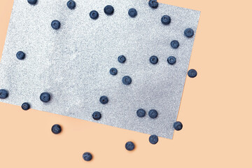 scattered blueberry berries on a beige and gray shiny background