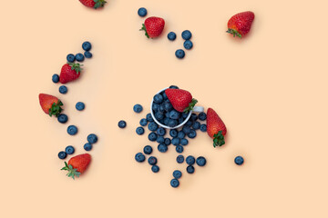 randomly scattered blueberries and strawberries on a beige background. top view, space for text