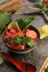 Spicy Thai Tom Yum Soup with Seafood, Served on Rustic Brown Bowl, on Green Wooden Background