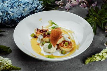 An ideal breakfast. Cottage cheese pancakes with caramel, almonds and cream sauce in a white plate. Ukrainian syrniki