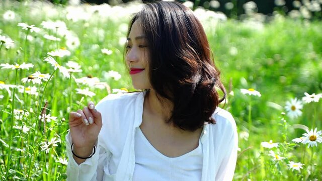 beautiful young asian woman relax in the spring blooming flower field
