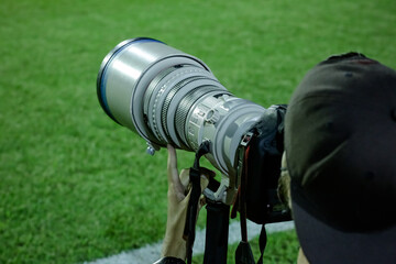 Lente de câmera fotográfica no campo de futebol olho no lance.
