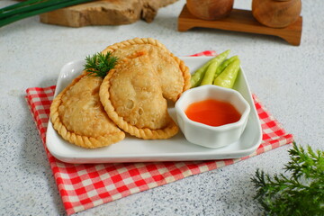 a plate of fried pastries containing vegetables served with sauce against white background