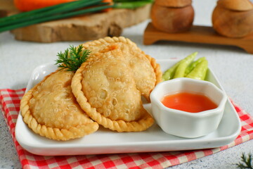 a plate of fried pastries containing vegetables served with sauce against white background