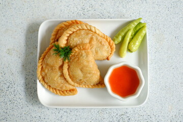 a plate of fried pastries containing vegetables served with sauce against white background