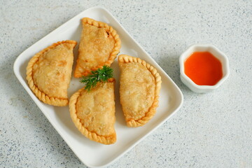 a plate of fried pastries containing vegetables served with sauce against white background 