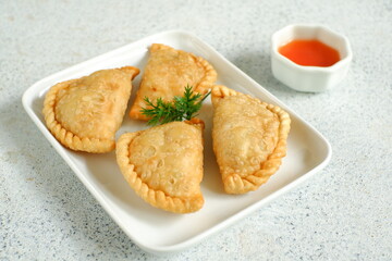 a plate of fried pastries containing vegetables served with sauce against white background 