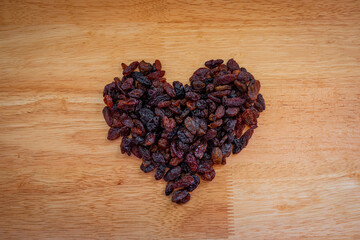 Black currant in the shape of heart on a wooden background