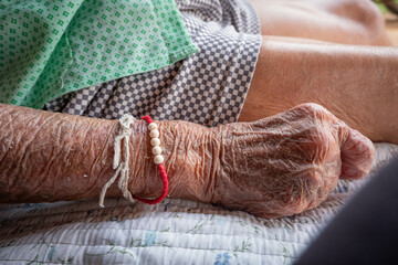 Close up wrinkled skin of old senior woman hands, bedridden patient