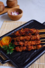 a plate of grilled chicken in bamboo skewer named satay against white background 