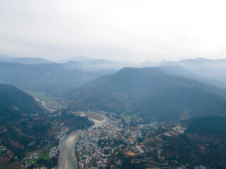 Fototapeta premium Aerial view of Bageshwar city in uttarakhand. Drone shot of a city situated in the banks of a river in mountains.