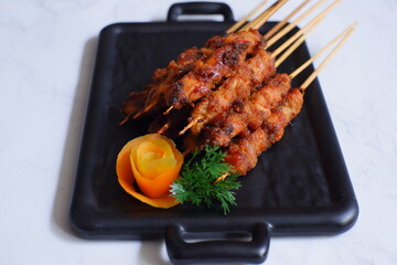 a plate of grilled chicken in bamboo skewer named satay against white background 