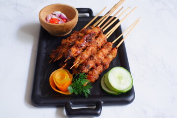a plate of grilled chicken in bamboo skewer named satay against white background 