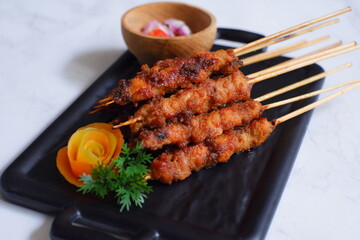 a plate of grilled chicken in bamboo skewer named satay against white background 
