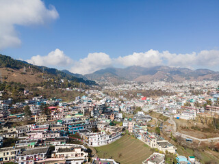 Fototapeta na wymiar Aerial view of a Pithoragarh. Drone shot of a city situated in between the mountains.
