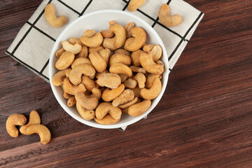 Top view of cashew nuts in white bowl on the table, Flat lay, Healthy snack, Vegetarian food.