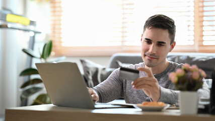Handsome man making payment online or banking online with computer laptop.