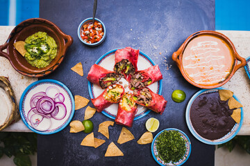 Delicious traditional Mexican condiments and dishes on dark surface