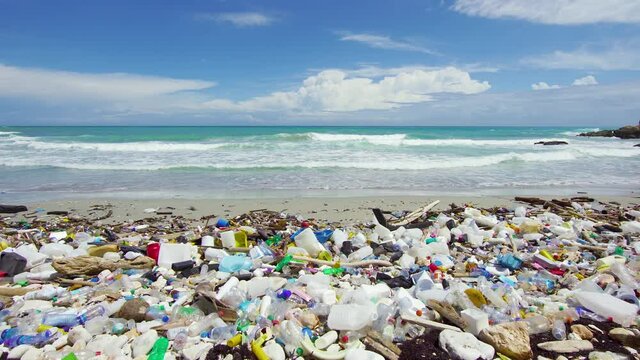 Pollution of the oceans with plastic waste. Sea waves crash on a dirty tropical beach. Sea coast with garbage. Global ecological catastrophe. Threat to the life of the environment.
