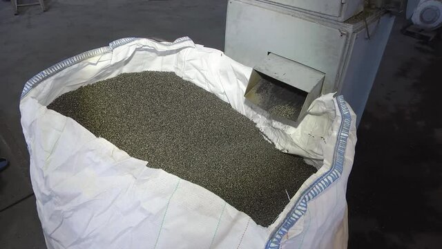 Close-up of Black plastic polymer granules. Flakes from recycled plastic bottles in a bag. Modern equipment for processing and sorting plastic waste.