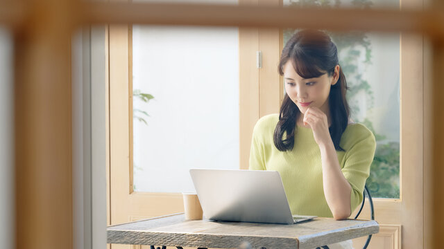 カフェでノートパソコンを使って仕事をする女性