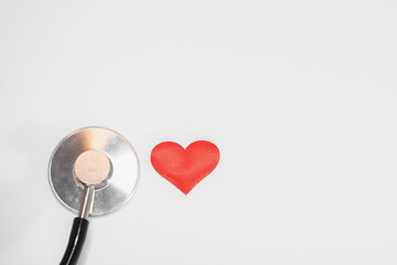 Stethoscope or phonendoscope lies near one single kid or child small red hearts: medical cardiological concept of saving many lives, statistics of cardiovascular diseases - obrazy, fototapety, plakaty