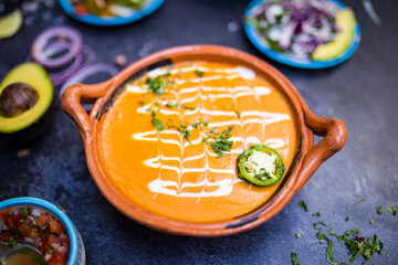Delicious soup in traditional clay pot above dark surface