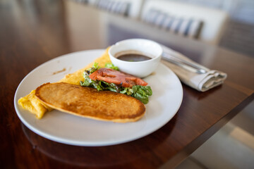 Plate with tasty omelet, vegetables, toast, and beans above brown table