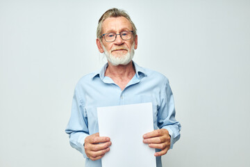 old man in a blue shirt and glasses a white sheet of paper light background