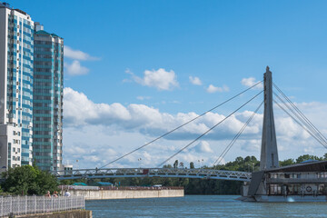 Fototapeta premium Cable-stayed bridge over the Kuban River and a multi-storey house on the embankment. Urban landscape