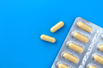 The drug in capsules and in a tablet on a blue background of light yellow color.