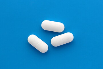 Three white oblong tablets lie on a blue background.