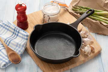 Cast iron skillet on a wooden board with kitchen items.