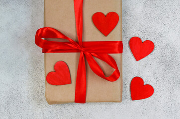 valentines day greeting card close up, festive gift box with red ribbon and wooden decorations shape heart, eco craft package and zero waste holiday