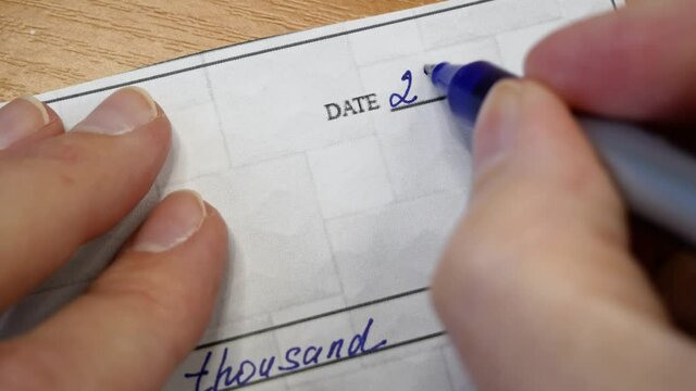 Check Financial Payment, Paycheck in hand on table background, Hand Holding Paycheck Or Payroll Check