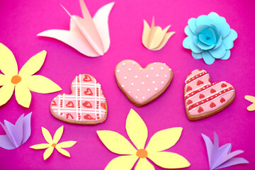 Paper art, bright handmade summer holiday flowers, craft on a pink background with cookies in the form of hearts. Colorful greeting card for Mom's day, Easter, Valentine's Day