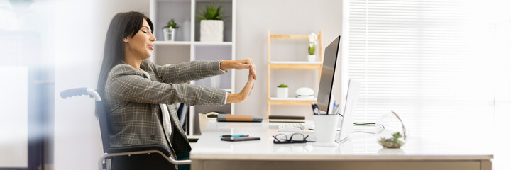 Woman With Disability Stretching At Desk Working