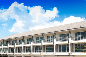 An oblique view of the facade of a row of buildings. Under the blue sky with white clouds.